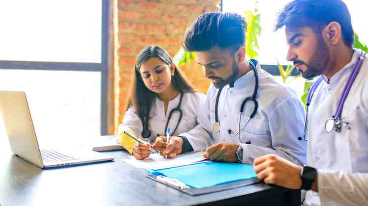 A group of medical students studying for their Step 2 exam, sitting in front of a lap top.